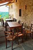 Dining tables and chairs next to stone wall on roofed terrace