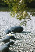 Summer party on river bank: rocks painted grey with stripes as decoration on pebble shore