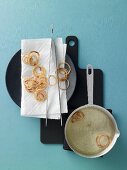 Onion rings being fried and dried on kitchen paper