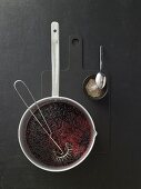 Cornflour being stirred into elderberry sauce