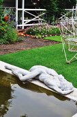 Pond with concrete surround and statue in tidy garden