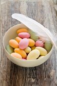 Sugared almonds in a bowl with a feather
