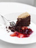 Half-eaten chocolate cake with berry sauce