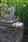 Stone figurine on stack of stone slabs in garden