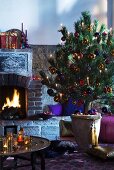 Christmas tree in ceramic pot in front of brick fireplace with Oriental tray table in foreground