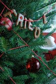 Weihnachtsbaum mit rotem Apfel, Wollschnur, Glaskugel und Schokobuchstaben