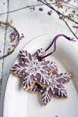 Plätzchen in Schneeflockenform verziert mit lila Zuckerguss