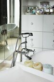 Free-standing bathtub with vintage tap fittings next to mirrored wall