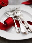 Forks and a red ribbon on a white plate