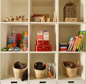 Toys and books in white shelving unit