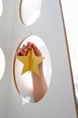 Child's hand decorating white plywood Christmas tree