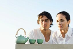 Couple outdoors, looking at tea set, smiling