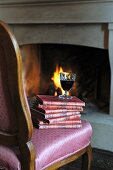 Glas Rotwein auf Stapel mit Büchern am Kamin