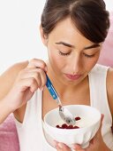 Woman eating yogurt with raspberries