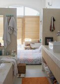 View from open-plan bathroom area - bed on floor in front of closed bamboo window blinds in loft-style interior