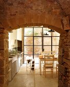 View though open stone doorway of table in front of terrace doors in kitchen-dining room