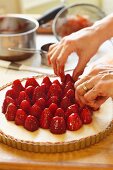 Woman's Hands Placing Glazed Strawberries on a Tart