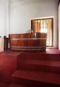 Steps leading up to wooden bathtub on red-painted platform