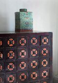 Oriental porcelain jar with lid on wooden chest of drawers painted with patterns