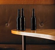 Three brown glass bottles on kidney-shaped table in front of leather sofa