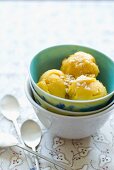 Drei Kugeln Mangosorbet mit Kokosflocken