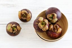 Mangosteens in a bowl and next to it