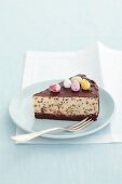 A slice of cheesecake with chocolate chips, chocolate glaze and sugar eggs