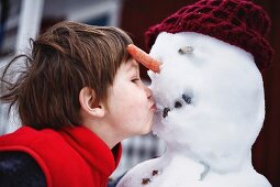 Close up of boy kissing snowman