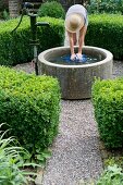 Woman filling watering can from well