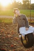 Girl sitting on a tyre swing in park