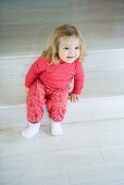 Blonde toddler girl sitting on steps, smiling