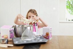 A little girl kneading dough