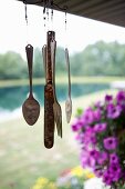 antique silverware wind chime hangs on porch of country home