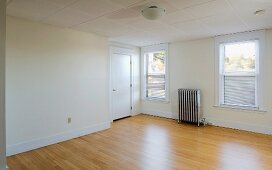 Empty room in apartment with hardwood floor and heater