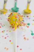 Gelber Cake Pop mit bunten Zuckersteuseln
