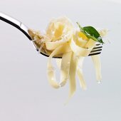 Tagliatelle, oil, basil and grated Parmesan on a fork