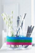 Glass containers used as cutlery holders and decorated with rubber bands