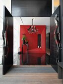 Blick durch offene Flügeltür in modernen Vorraum auf rote dreidimensionale Wand