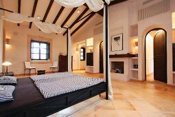 Elegantes Himmelbett mit Vorhang in Schlafzimmer eines mediterranen Landhauses