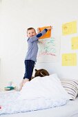 Boy hanging drawing on bedroom wall