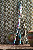 Colourfully painted sticks and baskets against patterned wall hanging