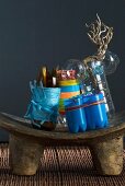 Artistically upcycled every-day objects - plastic bottles cut up and tied with colourful ribbons on rustic wooden footstool