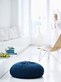 Sitzkissen mit selbstgestricktem, blauen Überzug in minimalistisch weiss gestalteter Wohnumgebung