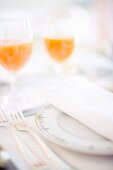 A place setting with a napkin and glasses of juice