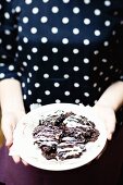 Frau hält Teller mit Schokoladen-Haselnuss-Keksen
