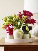 Verschiedene Frühlingsblumen in Vasen auf Holztisch