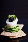Boiled egg filled with lumpfish caviar and cucumber slices on crispbread