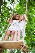 Smiling girls standing on tree swing