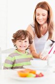 Mother pouring cereal for son