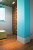 Baby blue masonry column and wood-panelled wall in window niche
